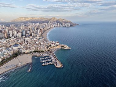 Açık okyanus ufkuna ve yumuşak kıyı şeridine sahip hava sahanlığı eğrisi marina ve kumlu kıyı şeridini süpürüyor.