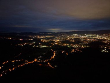 Dolambaçlı yol ışıkları vadiyi aydınlatıyor. Karanlık vadiden geçiyor. Arka farlardan oluşan yılansı bir şerit uzak mesafeye doğru gidiyor.