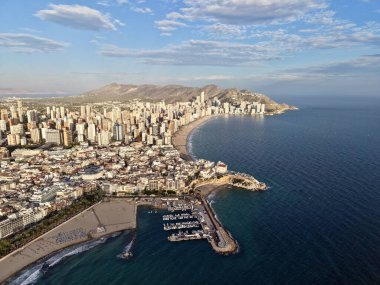 Hava limanı ve limanı demirlemiş yatları ve şehir silueti olan liman yetkilileri rıhtımları teftiş ediyor.