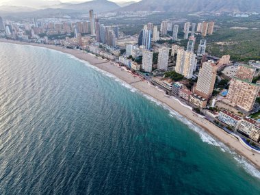 Şafak vakti hava sahili kıvrımlı kumsalları, sakin denizi ve kıyı şeridi boyunca uzanan gökdelen kümelerini gösteriyor.