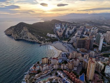 Gün batımında hava sahili silüeti, kumlu körfez boyunca lüks kuleleri araştıran emlakçı.