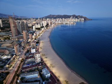 Akşamlık tatil beldesi, kıyı şeridi boyunca parlak ışıklar, yoğun gezinti güvertesi ve neon yansımaları, okyanus eğrisi
