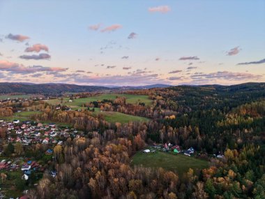 Köy kıyısı, pastel gökyüzünün altında muazzam kozalaklı ormanla buluşuyor. Çatı ve şeritler yaban arazinin sınırında, doğal yaşam alanında.