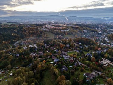 Sonbahar ormanı tarafından çerçevelenmiş hava kasabası. Mahalleleri, karışık çatıları, uzak endüstriyel bacaları gösteriyor.,
