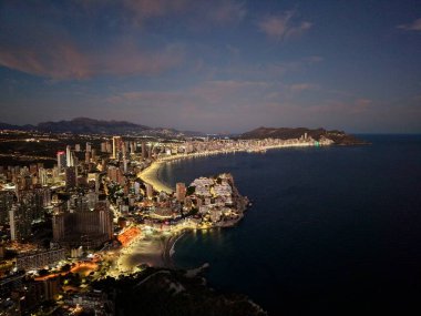 Geceleri deniz kenti aydınlanıyor, gezgin blogcu neon kıyı şeridini yakıyor ve kalabalık gezinti güvertesi, oteller yanıyor.