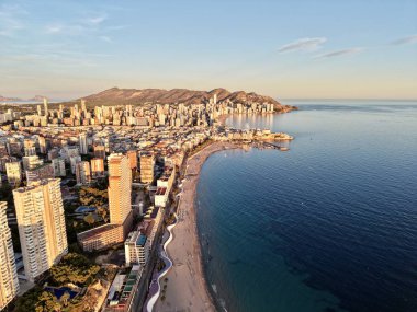Gün batımı kıyı şeridi ufuk çizgisi sıcak, yaşam tarzı tetikçisi suya turuncu yansımaları yakalıyor.