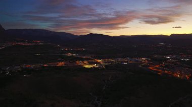 Geceleri uçan dağ kasabası, sıcak şehir ışıklarıyla aydınlatılan vadi boyalı gökyüzü, engebeli tepeler
