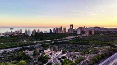 Yuvarlanan zeytinlikler ve uzaktaki doğal parklar ile kıyı günbatımının hava manzarası