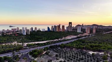 Coastal City Skyline Gün batımında, Sahil boyunca gökyüzü manzaralı Highrise Buildings, Otoyol Yeşil Parkland 'ı geçiyor