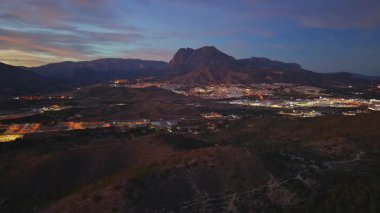 Alacakaranlık manzaralı Dağ Vadisi Işıkları ve virajlı yollar, uzak tepeler ve alçak yerleşim alanları