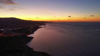 Alacakaranlık Kıyısı Hafif Dalgalar ve Dönen Teknelerle, Limanın Işıkları Mor Turuncu Gökyüzüne Parıldıyor,