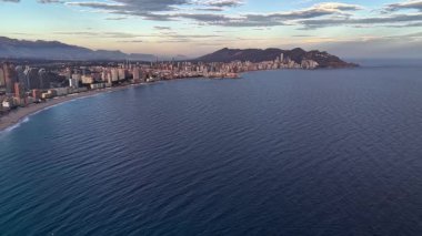 Sahil şeridinin ve sahil şehrinin hava kıvrımları, yumuşak dalgalar, geniş plaj, körfezin panoramik manzarası.