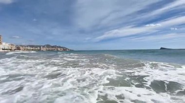 Deniz kenarına doğru köpüklü dalgalar, kıyı şeridinde sığ dalgalar ve karamsar dalgalarla gelen dalgalar.