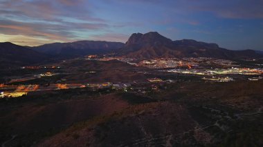 Alacakaranlık manzaralı Dağ Vadisi Işıkları ve virajlı yollar, uzak tepeler ve alçak yerleşim alanları