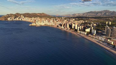Modern Skyline 'lı Aerial Sunlit Gezinti Alanı, Açık Deniz' deki Altın Yansımalar, Long Sandy Sahili