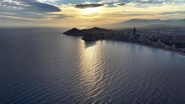 Gün batımı Parıltısı Sakin Akşam Denizi 'nde Uzun Altın Yol Kalıpları Uzaktaki Şehrin Silüeti Kısaltması,