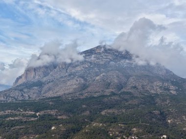 Bulutlara bürünmüş Puslu Dağ Zirvesi Teraslı Köy ve Çam yamaçları, dramatik ışık ve karamsar