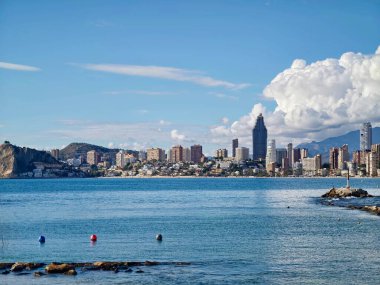 Coastal City Skyline, Blue Sea View Yüksek Binalar, Sakin Liman Suyu, Rocky Fronground ve Uzak