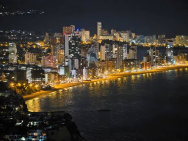 Serene Waterfront Skyline Altınla yıkandı, Sakin Deniz Yansımaları ve Uzak Yükseliş Silüetleri, Sessiz Gece