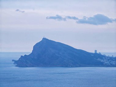 Sakin Deniz manzaralı deniz feneri, yumuşak mavi ışık, uzak liman ve sis, hafif dalgalar.,