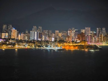 Geniş Sahil Ufku Geceleri Sakin Deniz 'de Parlayan, Katmanlı Işıklar Sahil Boyunca Ilık Kurdele Oluşturur