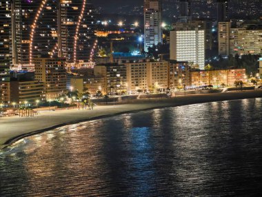 Kıyı yolu boyunca dekoratif ışıklarla özetlenmiş eğimli konut kuleleri, Ritmik Aydınlatılmış ön cepheler