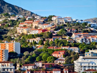Sunlit Hillside Teraslı evler, yoğun renkli çatılar, dar sokaklar ve merdivenler.