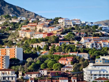Sunlit Hillside Teraslı evler, yoğun renkli çatılar, dar sokaklar ve merdivenler.