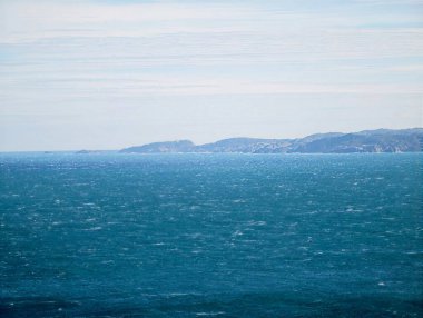 Minimalist Turkuaz Deniz Ufku ince yüzey dokusu ve uzak alçak kıyı şeridi ince gökyüzü