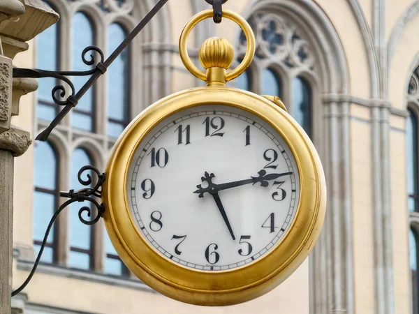 Taş cephede Altın Asma Saat, Süslü Parantez ve Roma Düğmesi Sabah Güneş Işığı Yumuşak Gölgeler,