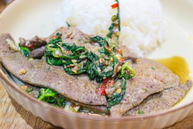 Detailed close-up of Thai Stir-fried Basil Pork Offal (Pad Krapow), showcasing glossy pork liver slices cooked with fiery chili and fragrant holy basil. An authentic, spicy, and popular Thai street food staple.