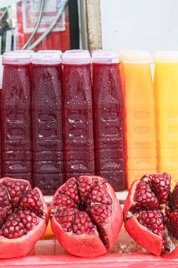 Freshly pressed Pomegranate Juice and Orange Juice bottles, chilled and arranged at a Thai street market. Glossy pomegranate arils highlight the natural, healthy, and refreshing qualities of this popular drink.