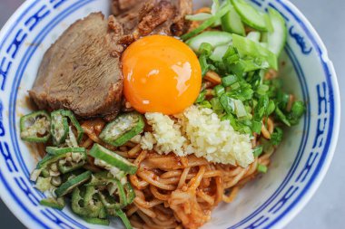 Thai-Sichuan style Red Pork Noodles (Ramen) with char siu, a raw egg yolk, and unique vegetable additions like okra. This rich and savory Thai street food is a delicious Asian fusion.