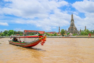 Wat Arun (Şafak Tapınağı), Chao Phraya Nehri 'nden görülen muhteşem bir Bangkok simgesi. Asya seyahatini ve zengin Tayland kültürünü sembolize eden süslü bir Tayland uzun kuyruklu teknesi geçiyor..