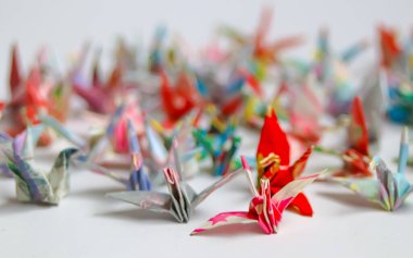 Beyaz üzerine çok renkli origami kağıt vinçler. Japon geleneksel umut, barış ve iyileşme sembolü (Senbazuru). Minimalist tasarım, kültürel tanıtım, yaratıcı altyapı ve farkındalık kavramları için idealdir..