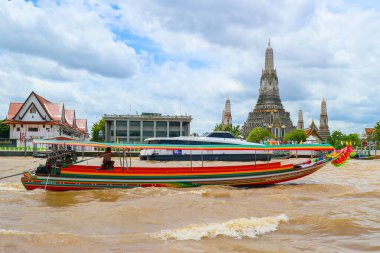 Bangkok Chao Phraya Nehri 'ndeki renkli Tayland uzun kuyruklu teknesinin arka planında Wat Arun' un görkemli zili. Temel seyahat, kültür ve simge imgeleri.