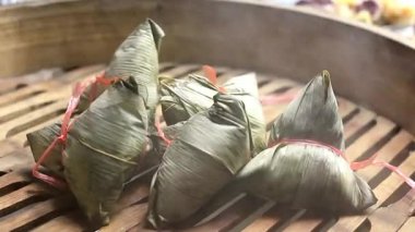 Geleneksel bambu sepetinde buharlaşan Zongzi 'nin (Çin Yapışkan Pirinç Böreği) yakın çekim videosu. Sıcak buhar yükseliyor, sıcak, şenlikli ve otantik Asya yemek pişirme sürecini vurguluyor.
