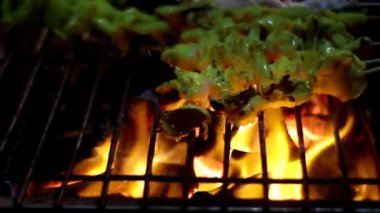 Sulu kalamar şiş ızgaralarının dinamik yakın çekimi sıcak bir barbeküde yoğun ızgara yapıyor. Kömürlere damlayan yağ muhteşem ateş patlamaları ve duman yaratır. Aşçılık, yemek hazırlama, yaz ızgarası ve egzotik sokak yemekleri için ideal..