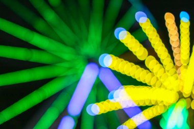 Dönme dolaptan çıkan neon yeşil ve sarı bokeh daireli soyut funk arka plan. Bir şehir festivalinde bir gece karnavalı ve hareketin heyecanını temsil eden canlı ışık izleri..