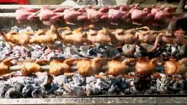 Hızla dönen bir rostoda dönen ızgara bıldırcın dinamiği. Altın kahverengi deri ve yoğun hareket, otantik sokak yemekleri, aşçılık amaçlı seyahat içeriği ve gıda reklamları için ideal.