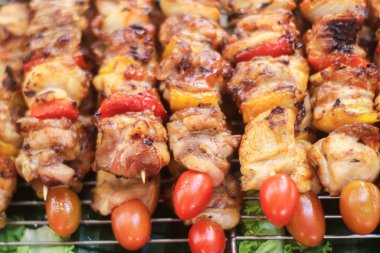 Kömürde kızarmış tavuk, domatesli barbekü şişi, evrensel sokak yemekleri, dumanlı açık hava yemek pişirme, günlük yemek kültürü ve küresel olarak tanıdık ızgara protein cazibesi.