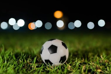 Arka planda bulanık stadyum ışıkları olan yeşil bir sahada futbol topu. Uluslararası bir turnuvanın tutku ve enerjisini temsil eden yüksek kaliteli sinematik görüntü, spor markaları ve haberler için ideal.