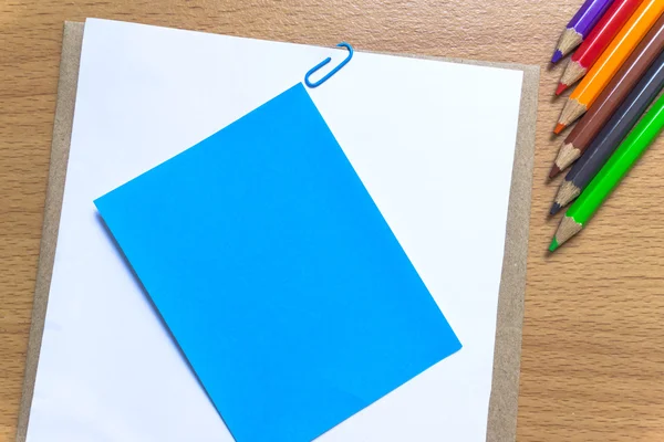 Papel en blanco y lápices de colores en la mesa de madera. Vista desde arriba . — Foto de Stock