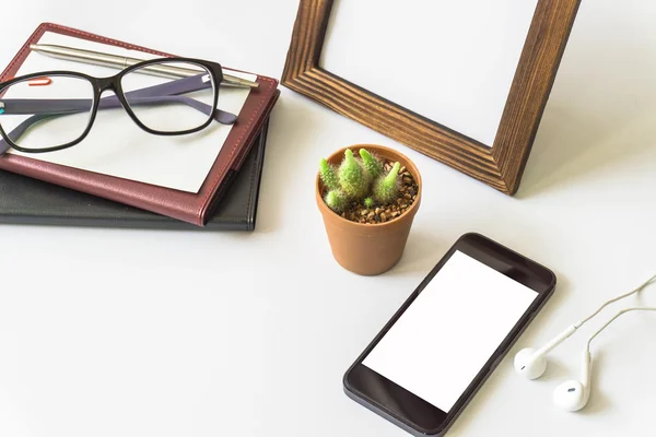 Office desk top view with smartphones, laptop eyeglasses and book.