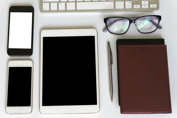 Office desk top view with smartphones, laptop eyeglasses and book.