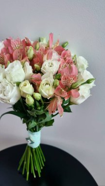 Beyaz ve pembe çiçeklerin uyumlu bir karışımından oluşan yuvarlak bir gelin buketi. Düzenleme beyaz Eustoma ve siyah masada pembe alstroemeria içeriyor.