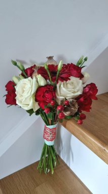 Çiçek ve haşhaş karışımından beyaz ve kırmızı yuvarlak bir buket, Ukrayna tarzı bir buket, ahşap merdivenlerde duran beyaz bir düğün buketi, çiçekçi konsepti.