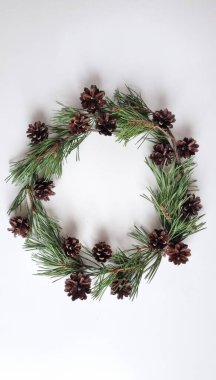 Beyaz arka planda çam kozalaklı doğal iğne çelengi. konsept arkaplan ve kart, çevre dostu dekorasyonlar, el yapımı