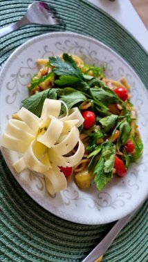 Beyaz dekoratif tabakta maydanoz ve kiraz domatesleriyle süslenmiş renkli bir sebze salatası yer alır..