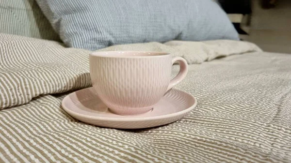 Pembe çay fincanı ve çay tabağı çizgili yatak, ev konforu, sıcak bir atmosferde çay tabağı ile pembe fincan, ekose, konfor konsepti, atmosfer, güzellik salonları.